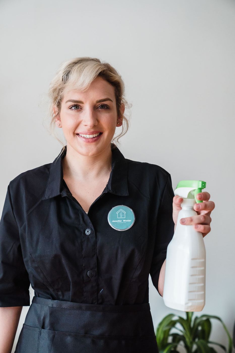 Smiling housekeeper holding a spray bottle in a bright home